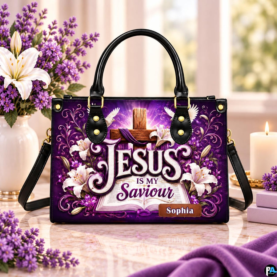Purple cross devotional handbag displayed on a marble tabletop beside a vase of white lilies and candle.
