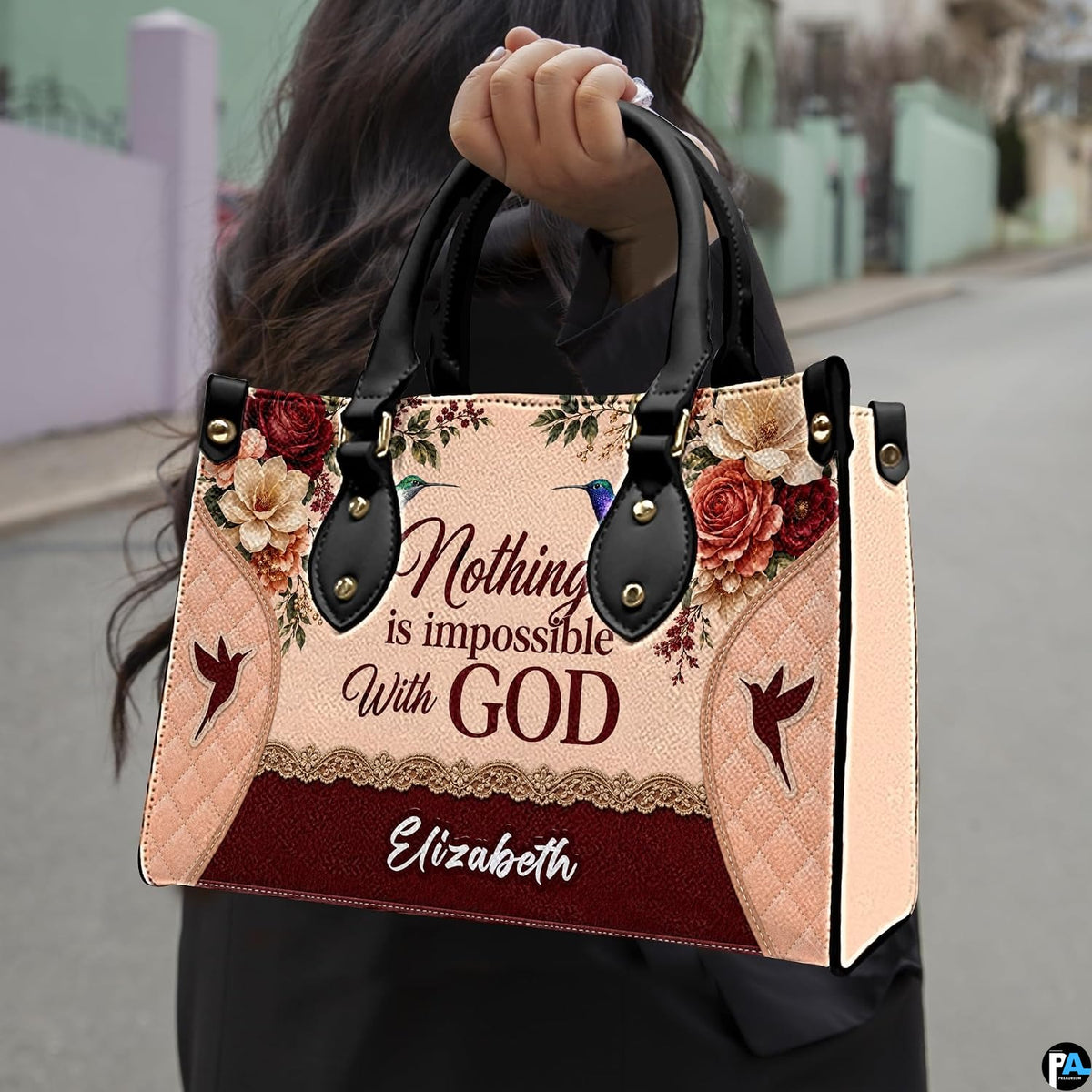 Outdoor lifestyle presentation showcasing the hummingbird devotional handbag carried by a model.