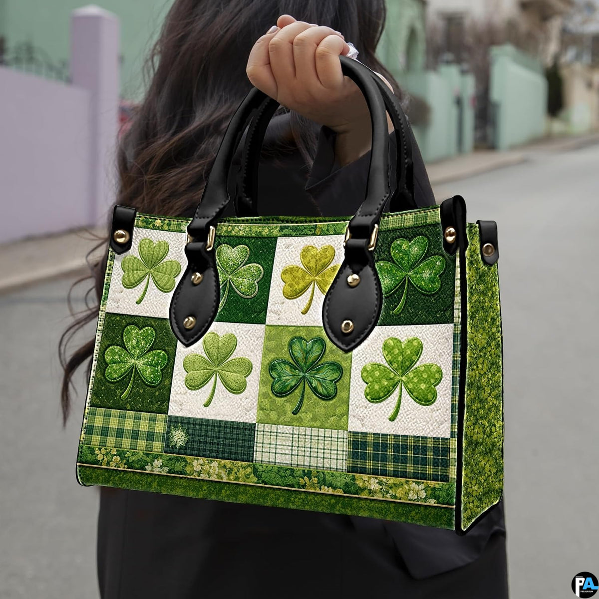 Model carrying green clover handbag with plaid and botanical collage