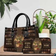 Handbag displayed beside matching zippered wallet with dragon library artwork on a wooden table