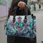 Model carrying the turquoise butterfly cross handbag with black top handles outdoors