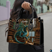 Three-quarter view of guardian dragon purse showing structured silhouette, handles, and gold studs