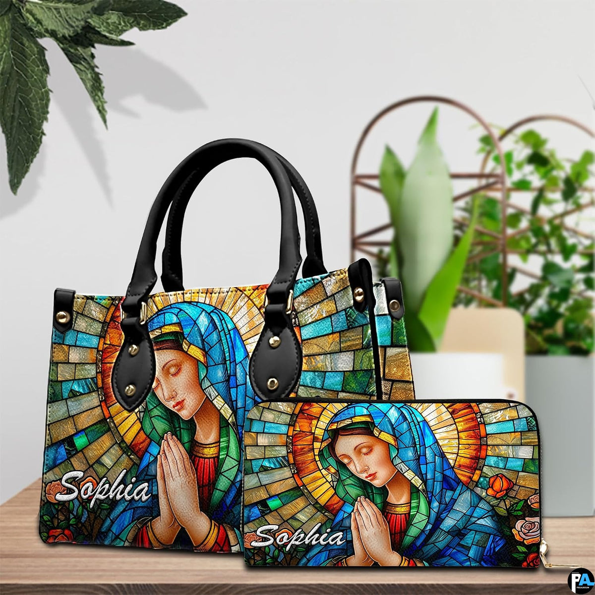 Handbag alongside matching companion piece displayed on wooden tabletop beside green plant.