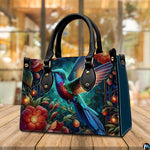 Back view of jewel hummingbird handbag showing continuous garden illustration on white background.