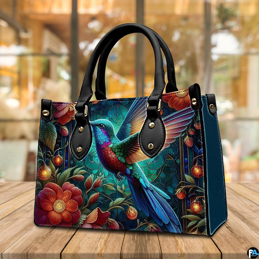 Back view of jewel hummingbird handbag showing continuous garden illustration on white background.