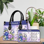 Floral cross handbag and wallet displayed on wooden table beside potted plant.