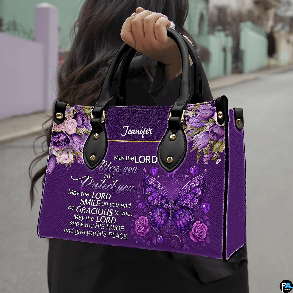 Christian blessing violet handbag held by top handle while walking outdoors along a residential street.
