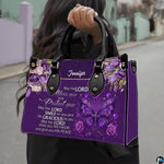 Christian blessing violet handbag held by top handle while walking outdoors along a residential street.