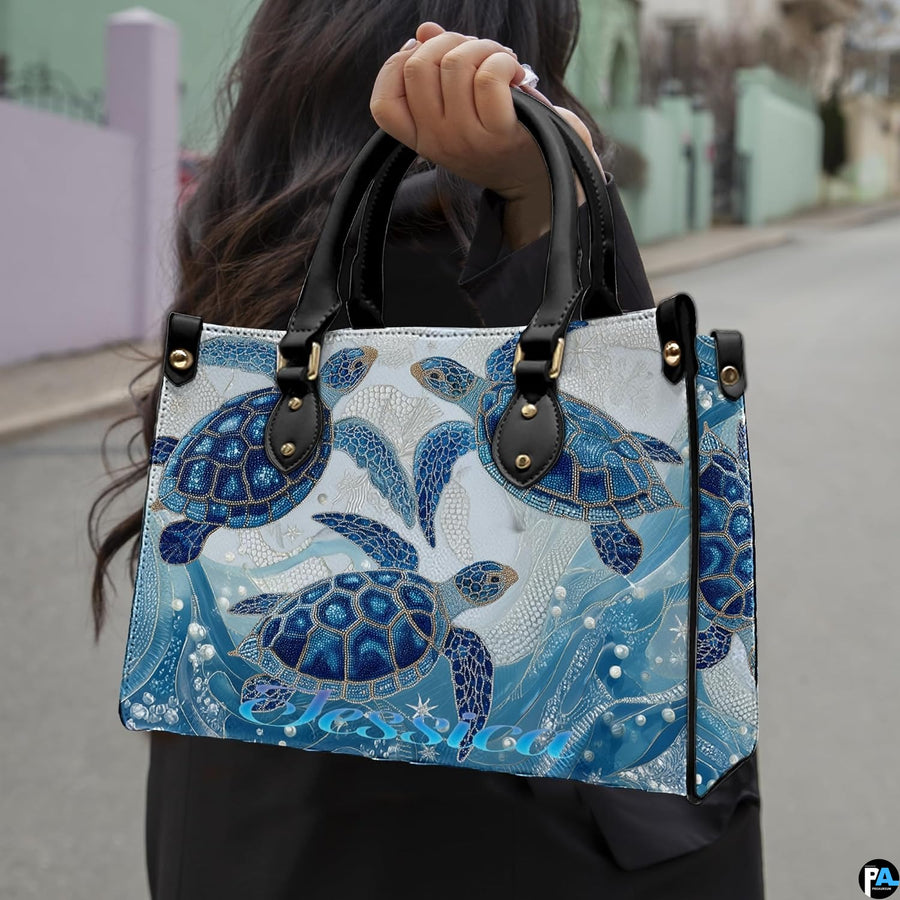 Front view of sea turtle handbag showcasing three detailed turtles in turquoise and cobalt blue.