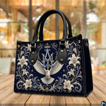 Tabletop display of Marian crest handbag highlighting white dove and golden scrollwork