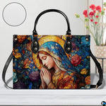 Praying Mary rose garden handbag displayed indoors on a white table beside flowers