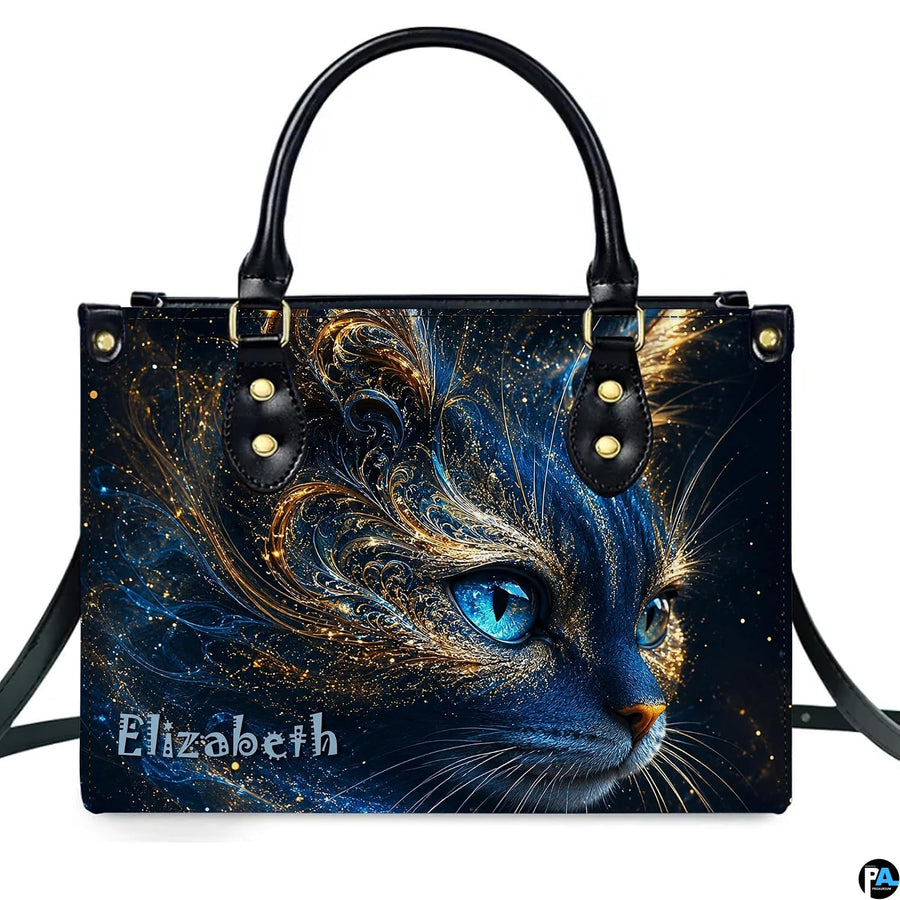 Studio presentation of cosmic blue cat artwork showing swirling gold filigree and glowing blue eyes on white surface.