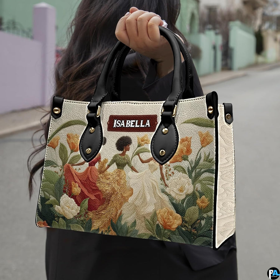 Model holding the botanical dancing women handbag outdoors along an urban street.