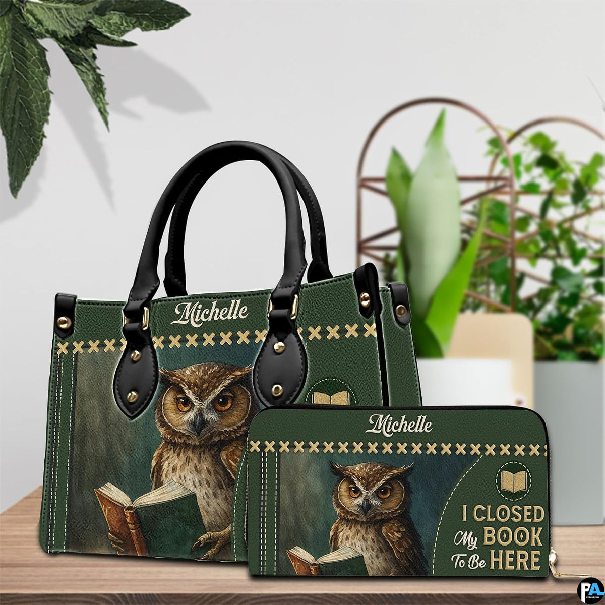 Reading owl handbag and matching wallet set styled on a wooden tabletop with indoor plants.