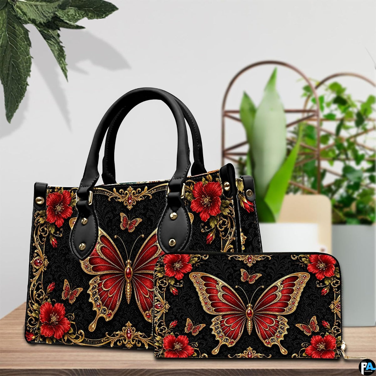 Pair showcase featuring baroque red butterfly artwork placed on wooden tabletop beside leafy potted plant.