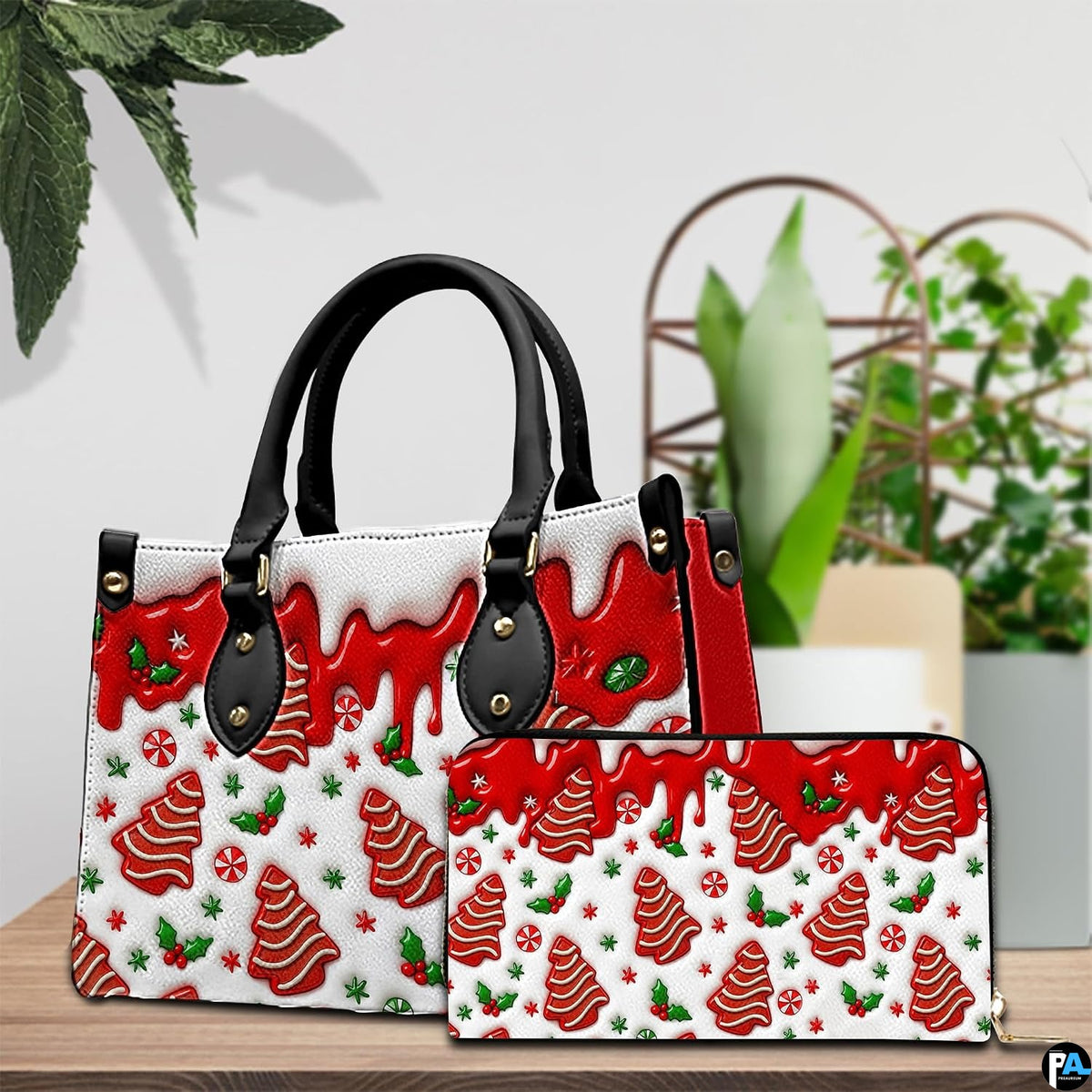 Tabletop staging of festive handbag and coordinating wallet displaying gingerbread tree and red drip artwork.