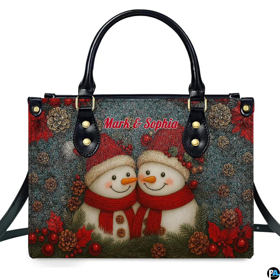 Front view of holiday handbag and wallet set with snowman couple in red beanies on teal glitter backdrop
