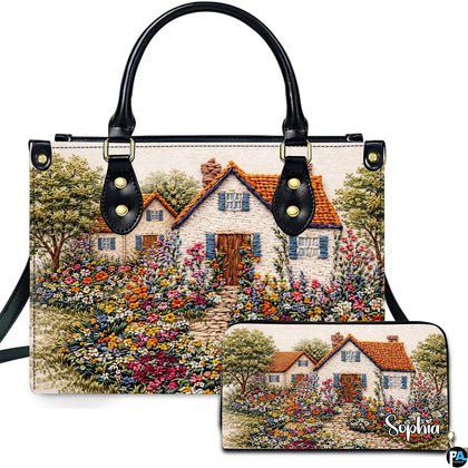 Embroidered country cottage and blooming garden artwork displayed on accessory set against white background.