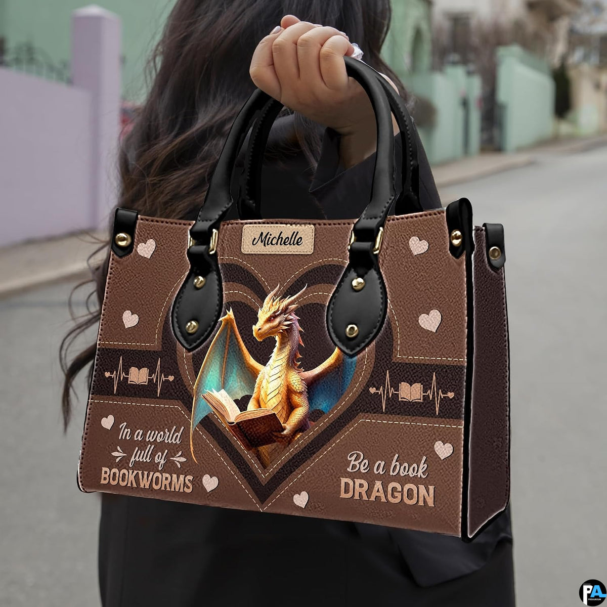 Model carrying golden dragon handbag by top handles on an outdoor street