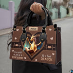 Model carrying golden dragon handbag by top handles on an outdoor street