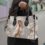 Side profile view of structured Madonna handbag showing silhouette and black carry handles