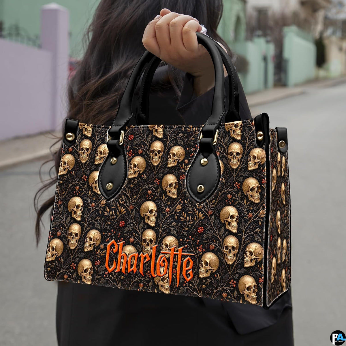 Outdoor street scene presenting the dark botanical skull graphic held in daylight against town scenery.