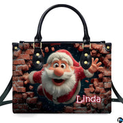 Front studio shot of cartoon Santa bursting through red brick wall on top-handle handbag.