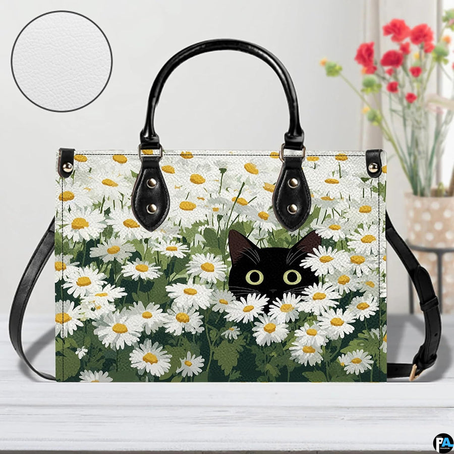 Front view of peeking black cat daisy art on white wooden surface beside red blossoms.