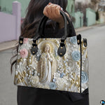 Lifestyle display of pearl framed Virgin Mary handbag carried by model showing artwork and scale