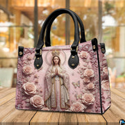 Tabletop display of Virgin Mary handbag highlighting sculpted pink roses and crowned figure