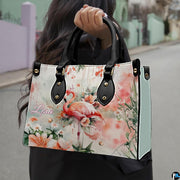Outdoor lifestyle view of the watercolor pink flamingo handbag carried by top handles.