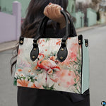 Outdoor lifestyle view of the watercolor pink flamingo handbag carried by top handles.