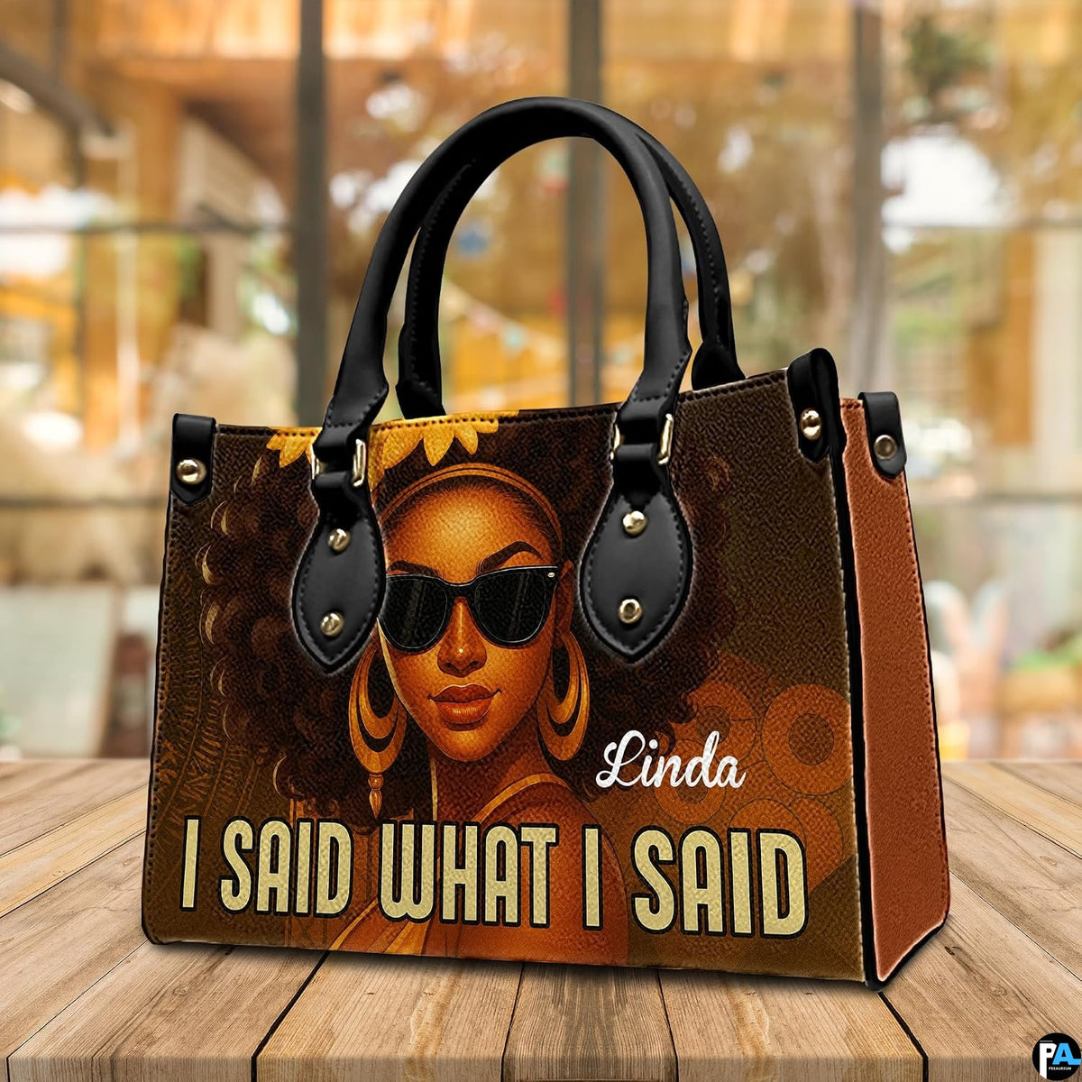 Angled display view of the afro queen handbag set atop a wooden surface in a bright interior.