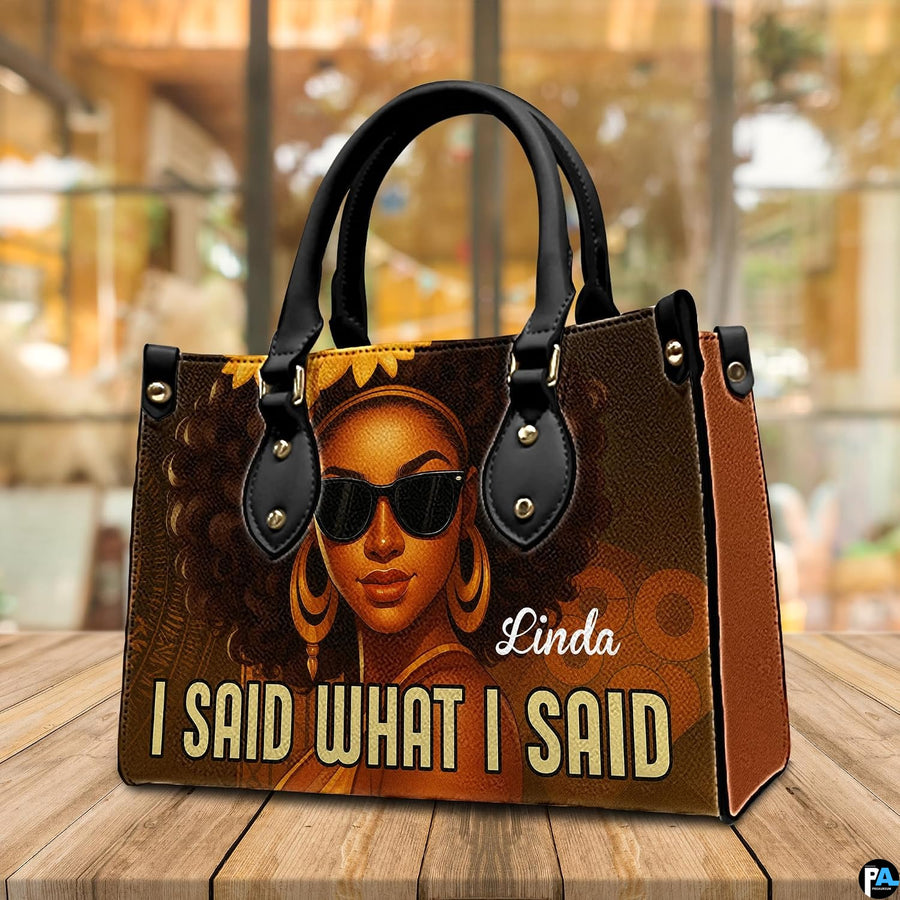 Angled display view of the afro queen handbag set atop a wooden surface in a bright interior.