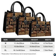 Library themed handbag and matching wallet set styled on a wooden tabletop with green plants.