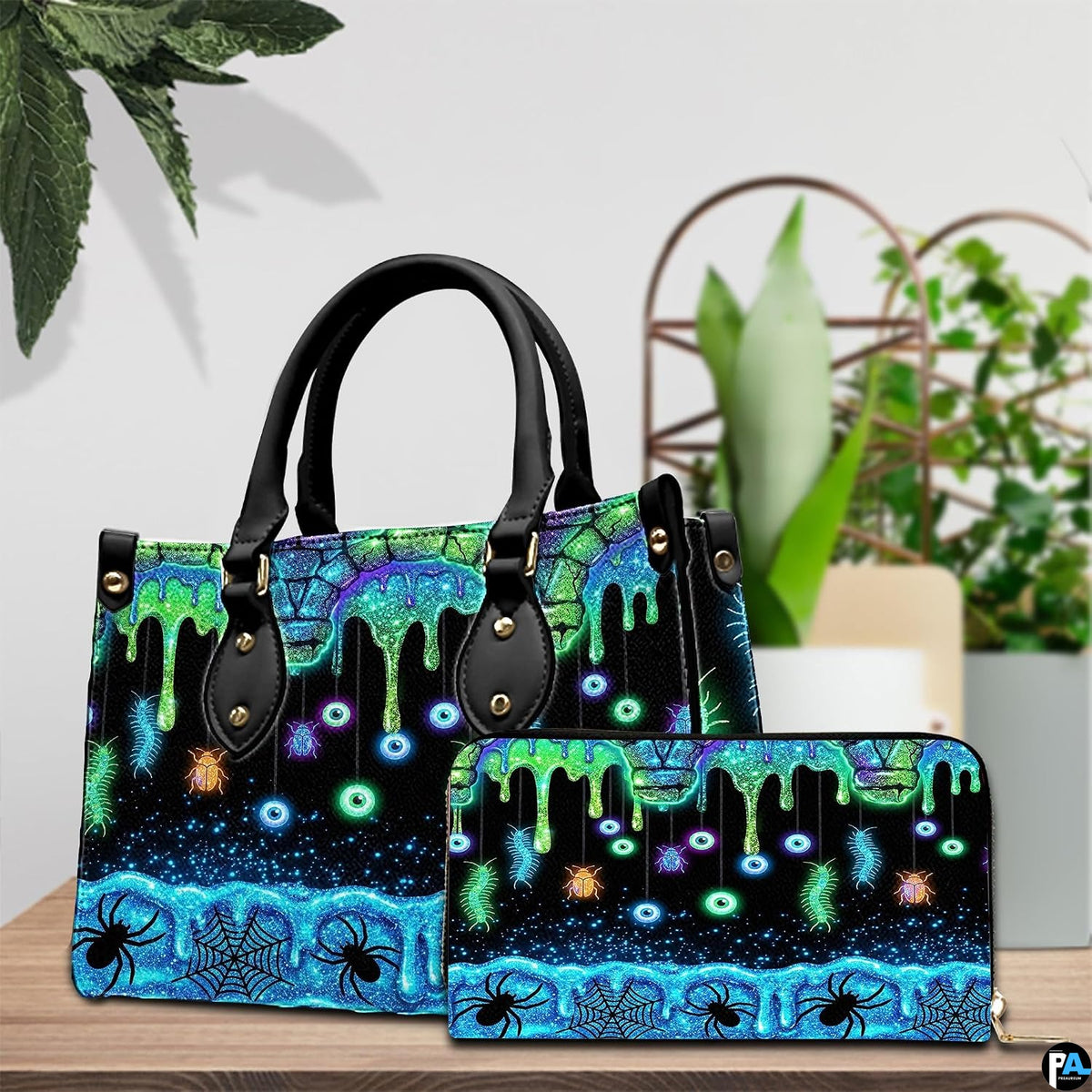 Neon eyeball handbag and wallet displayed on wooden table beside potted plant.