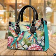 Back view of mosaic hummingbird handbag showing continuous colorful print on white background.