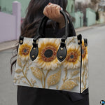 Side profile of sunflower handbag showing structured silhouette and black carrying handles.