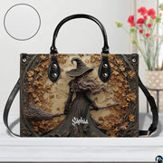 Gothic autumn witch handbag displayed on white table beside floral bouquet.