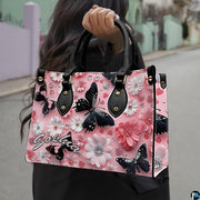 Front close-up view of handbag showing black butterfly and daisies