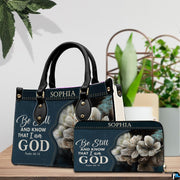 Devotional floral handbag paired with matching wallet on a tabletop near natural indoor greenery.