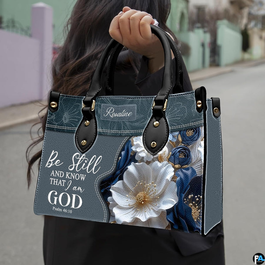 Front view of Bible verse purse showing slate blue panel, biblical text, and white floral bouquet.