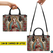Model walking outdoors carrying arched Our Lady of Guadalupe devotional handbag.