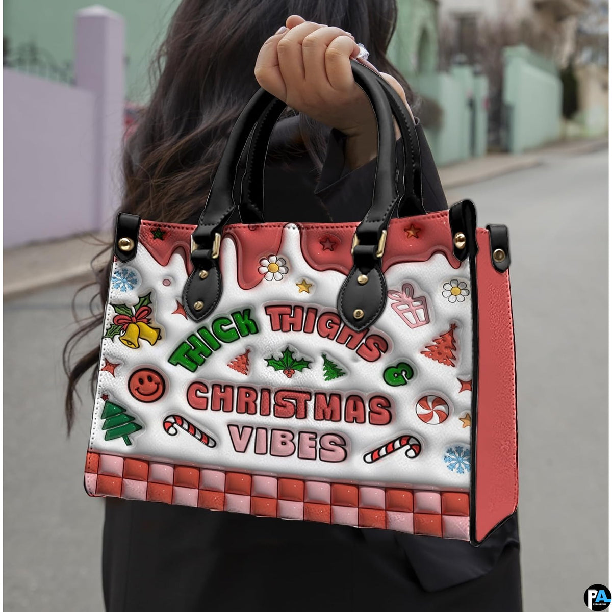 Handbag held outdoors showing colorful Christmas graphics and playful typography in natural light.