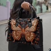 Woman carrying the sculpted bronze butterfly handbag outdoors on a street.
