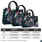 Studio front shot of midnight teal handbag showcasing outspread hummingbird wings and floral vines.
