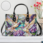 Back view of mosaic hummingbird handbag showing continuous floral pattern on white background.