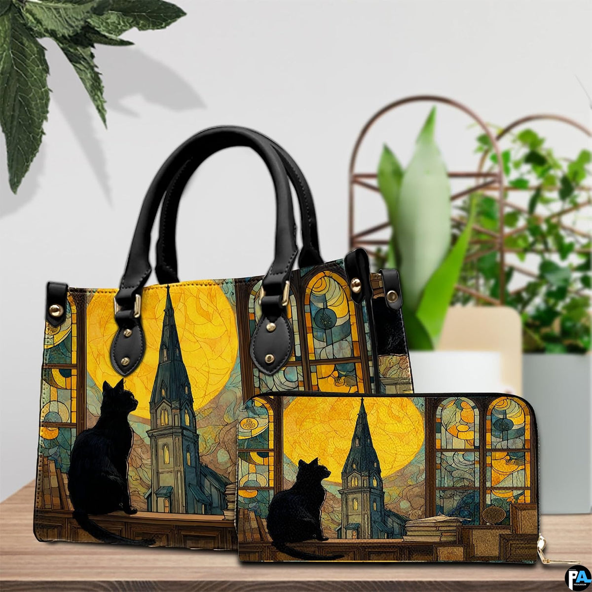 Cat stained glass window artwork resting beside potted plants on a wooden table.