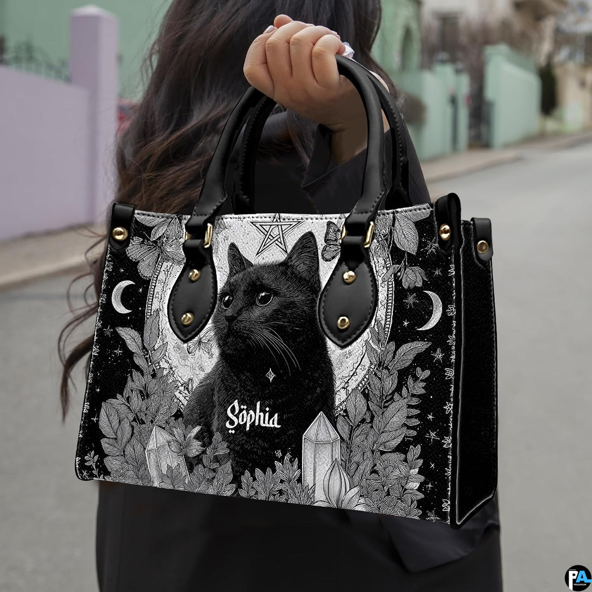 Gothic black cat handbag held by top handle while walking outdoors along a residential street.
