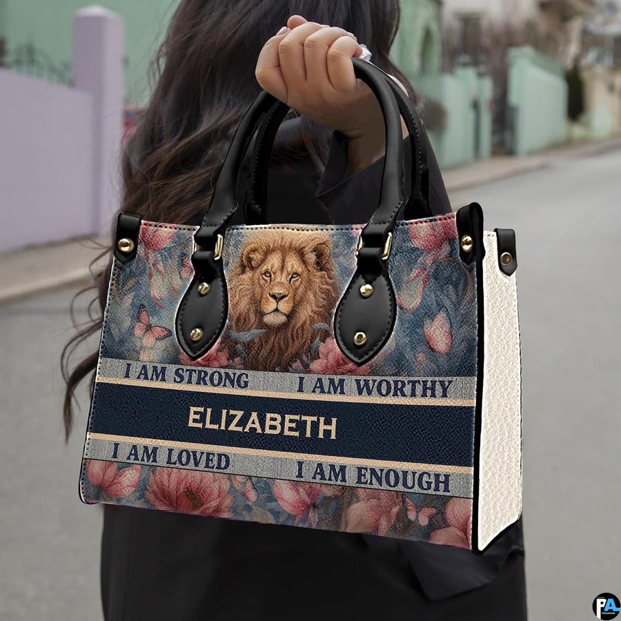 Lion portrait handbag carried outdoors by top handles showing the lion face and floral artwork.